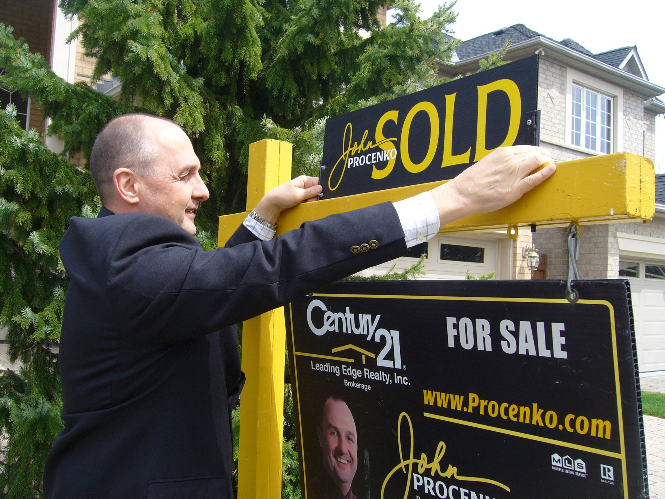 Real Estate Agent hanging sold sign